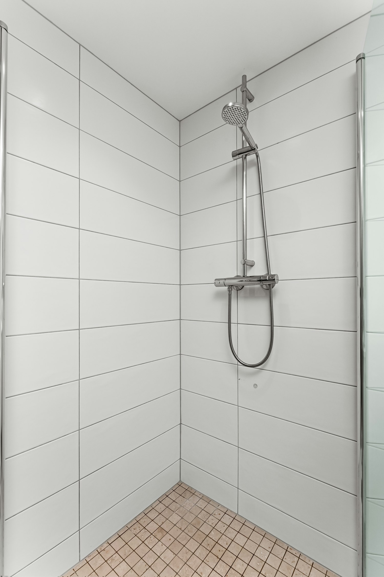 Walk-in shower with clean tile surround and faucet detail